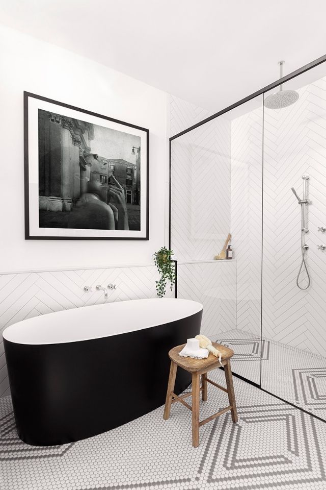 Black bathtub with glass-walled shower in black and white 