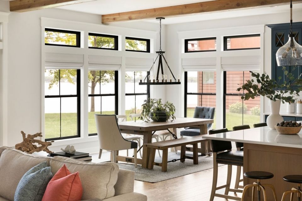 Open concept dining room in lake house with large black windows and rectangular dining table