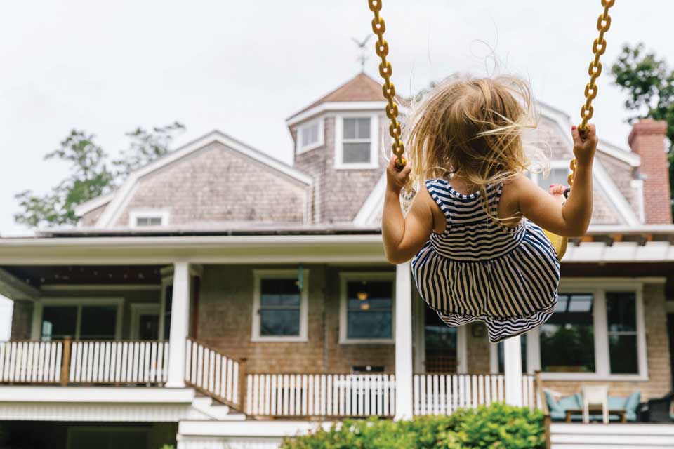 child on swing in front of house