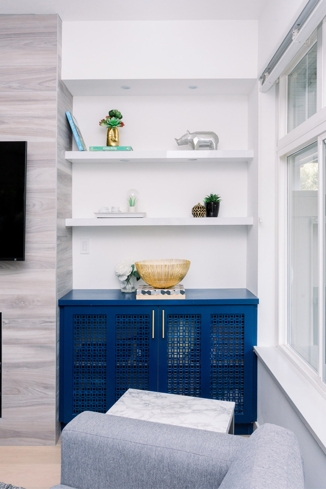 Blue cabinet and floating shelves in built-in next to stone fireplace 