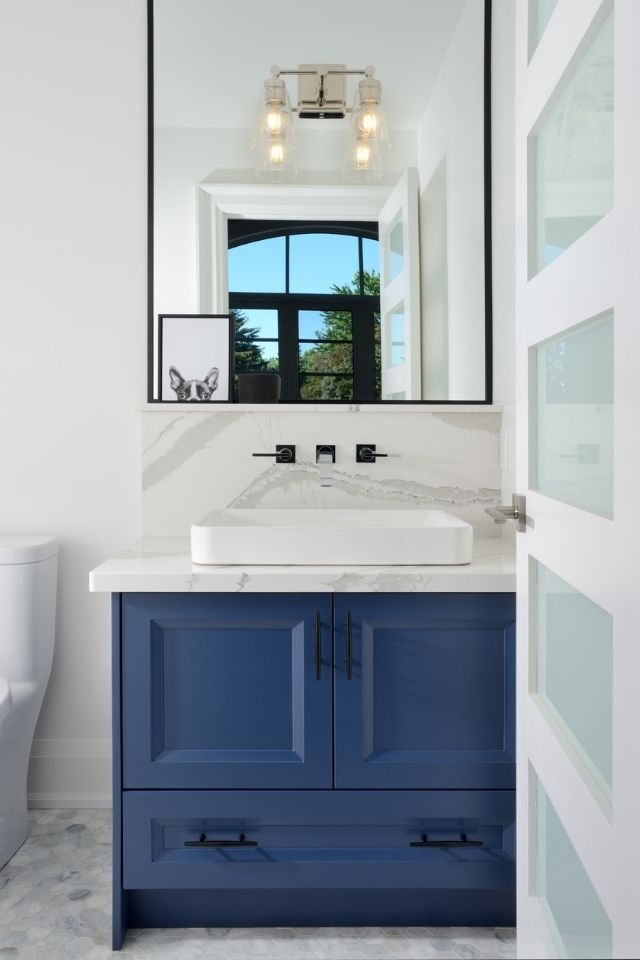 Blue bathroom vanity with stone tile and rectangular mirror 