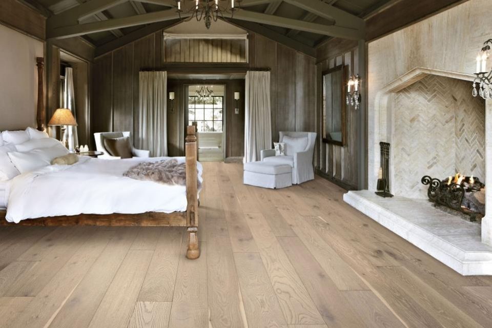 Farmhouse hardwood flooring in bedroom with fireplace and high ceilings 
