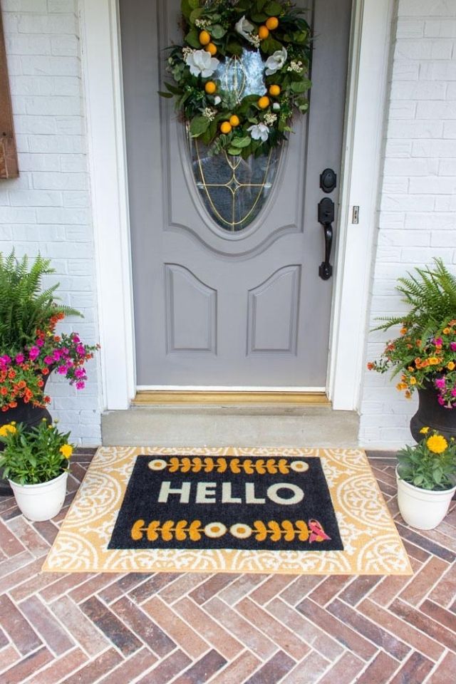 Gray front door with yellow hello welcome mat and citrus wreath