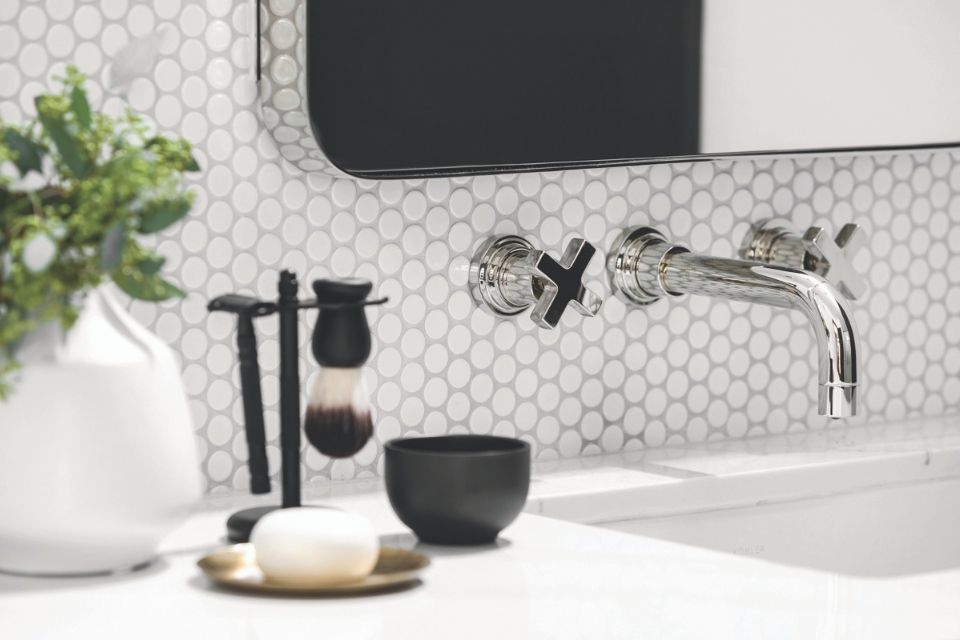 Close up of chrome sink with white round white tile in modern black and white bathroom 