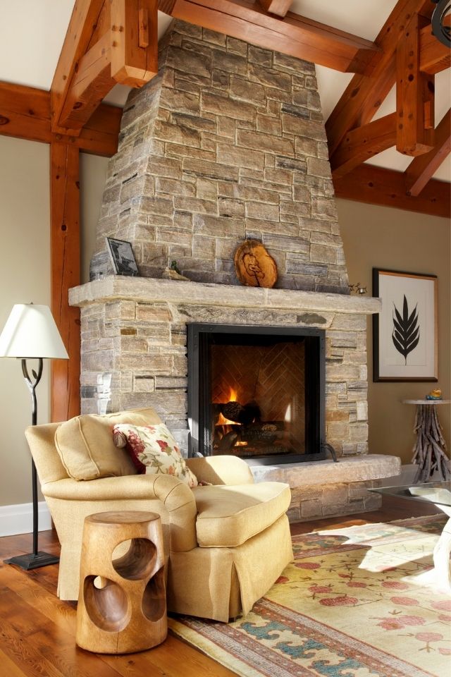 Stone fireplace in warm and cozy mountain home with fireplace on and chair