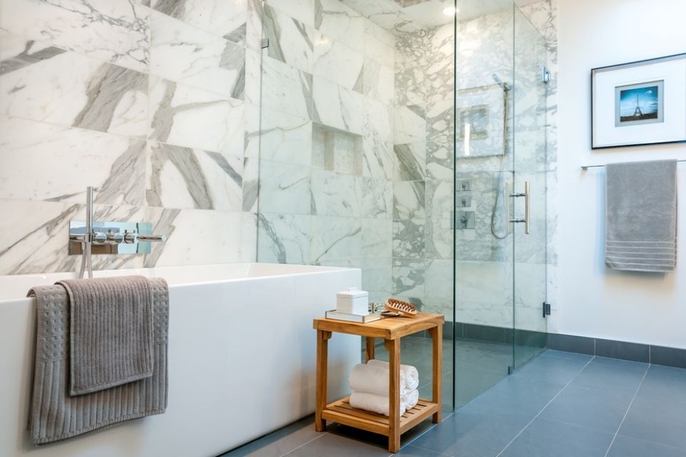 Dark gray tile floor and white shower walls in walk in shower in large bathroom 