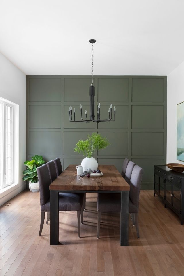 Dark green board and batten wall in dining space with modern furniture