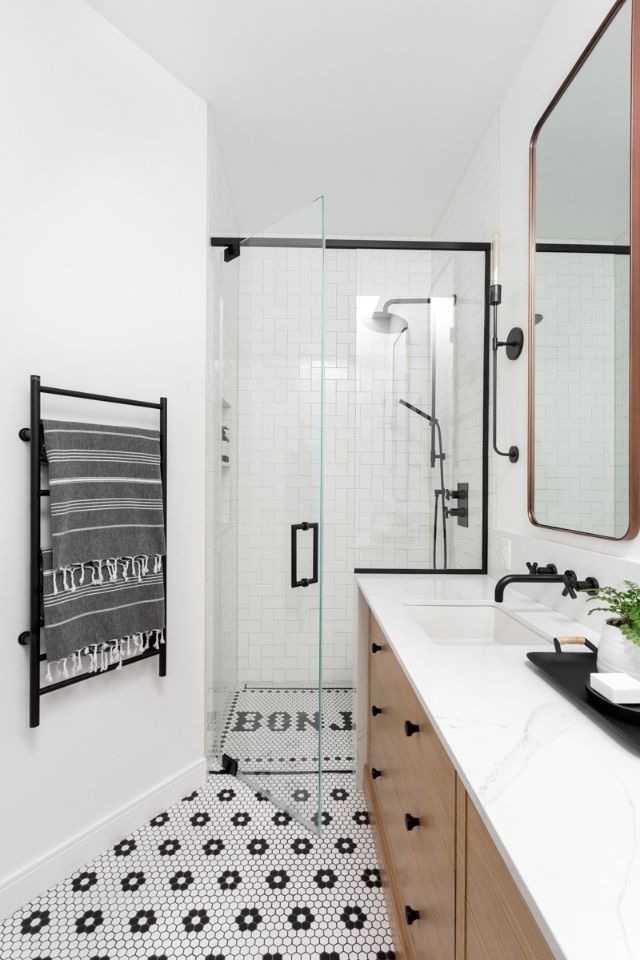 Custom black and white bathroom with glass shower doors and oak vanity 