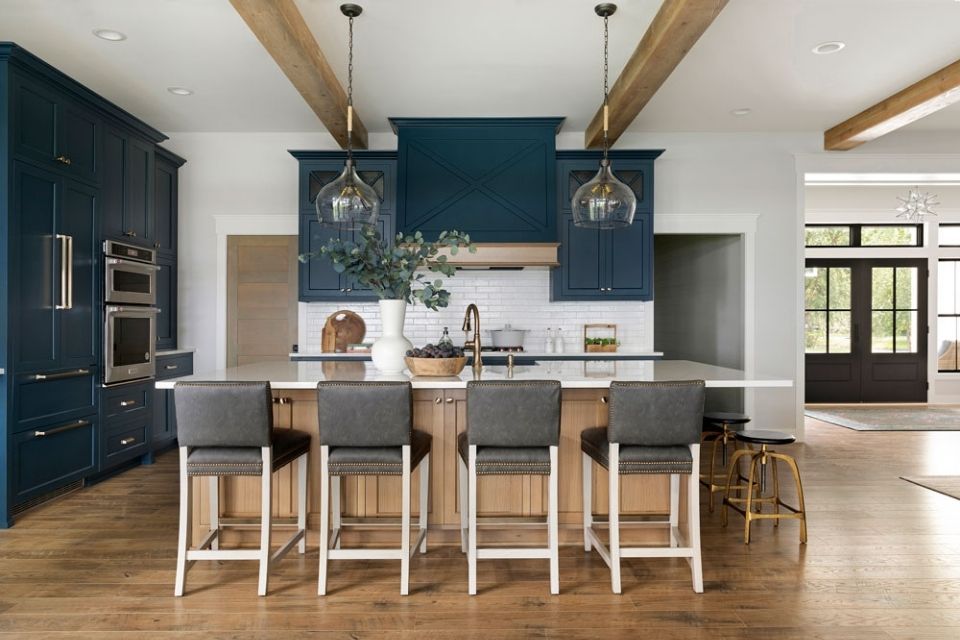 Dark blue kitchen with wooden island and comfortable barstool seating 