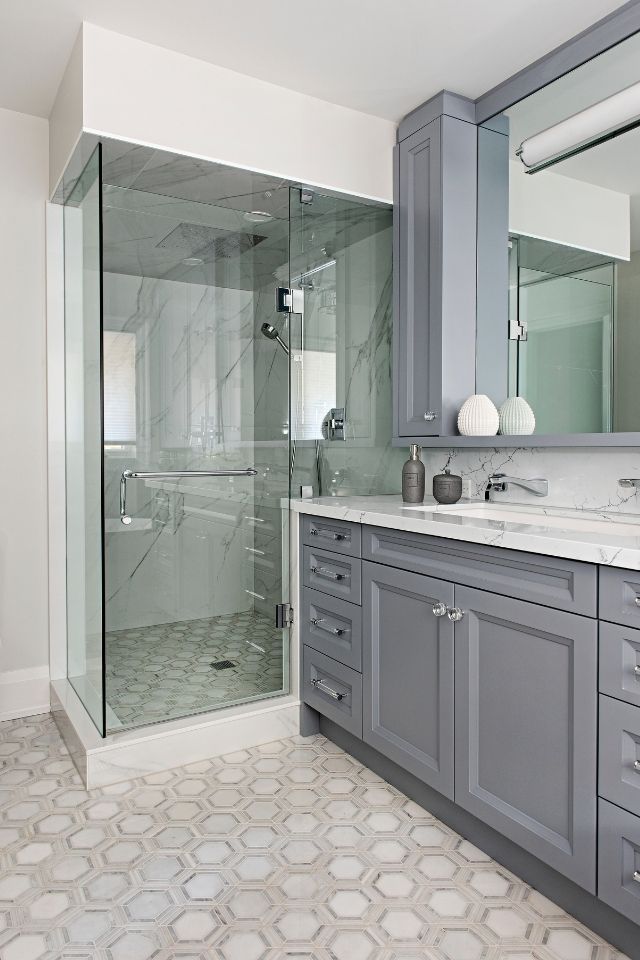 Dark gray cabinetry in bathroom with white tile and walk in shower 