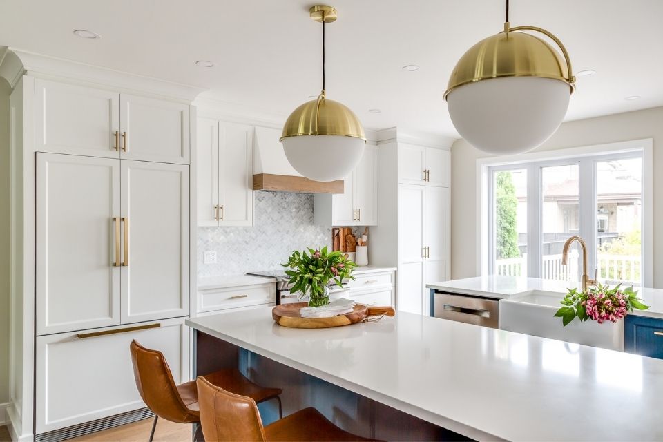 Gold and white globe light fixtures in updated white kitchen with blue cabinets 