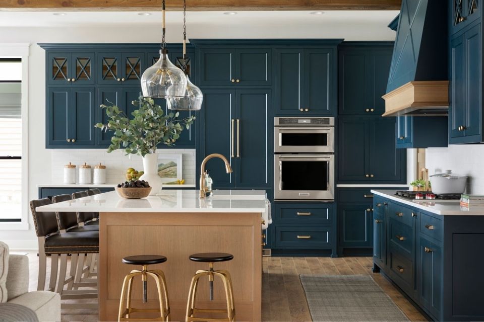 Dark blue kitchen cabinets with wood accents and brass in lake home with island 