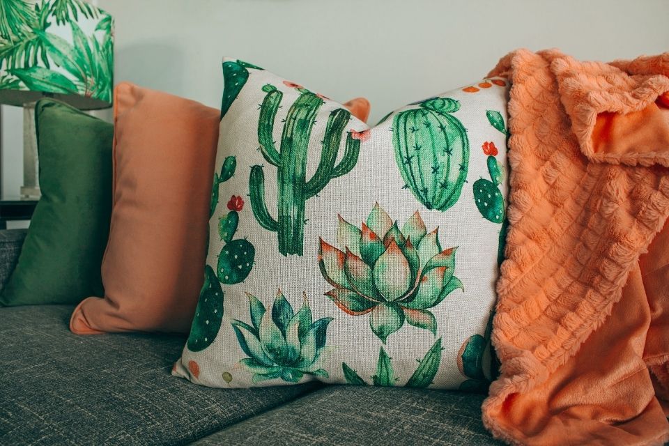 Cactus pillow and orange throw blanket on couch 