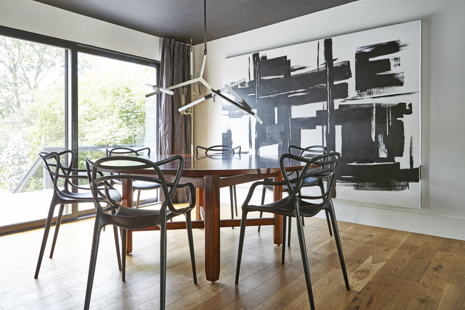 Minimalist dining room with large artwork and black chairs 