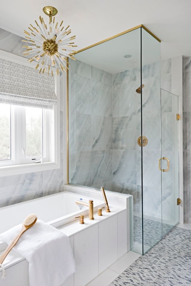 Glass enclosed walk in shower in chic white and gold bathroom 
