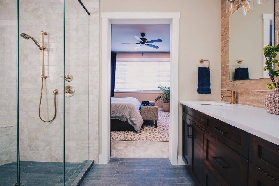 Glass surrounded walk in shower in spacious bathroom with gold hardware