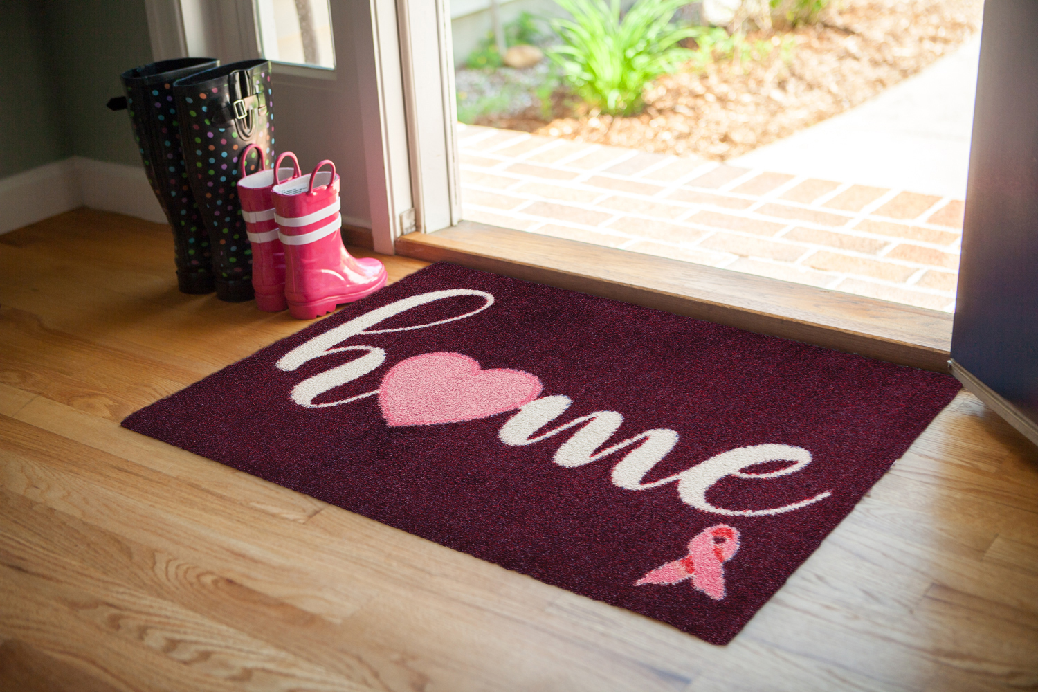 Maroon welcome mat in entryway of home with hardwood flooring 