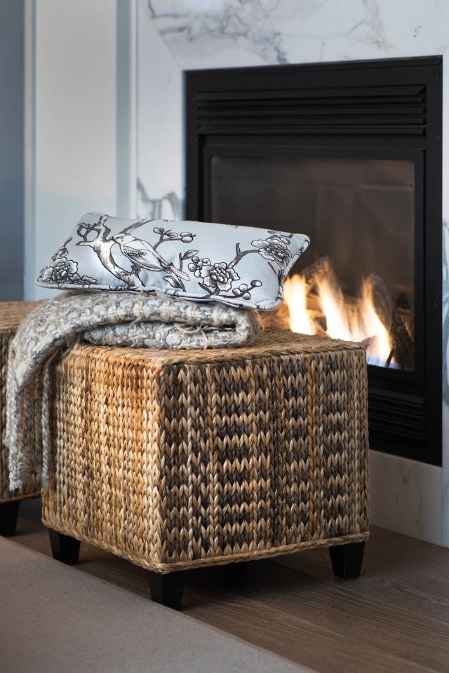Seating in front of a fireplace with a warm blanket and a throw pillow