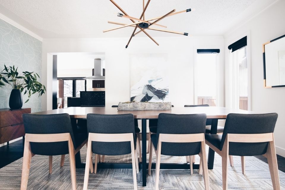 Mid-century modern dining room with gray cloth chairs and gold light fixture 