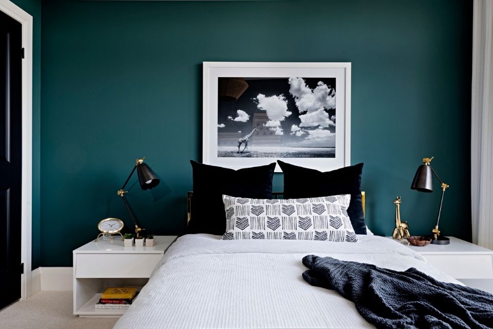 Dark blue wall in bedroom with art by Rebecca Hay 