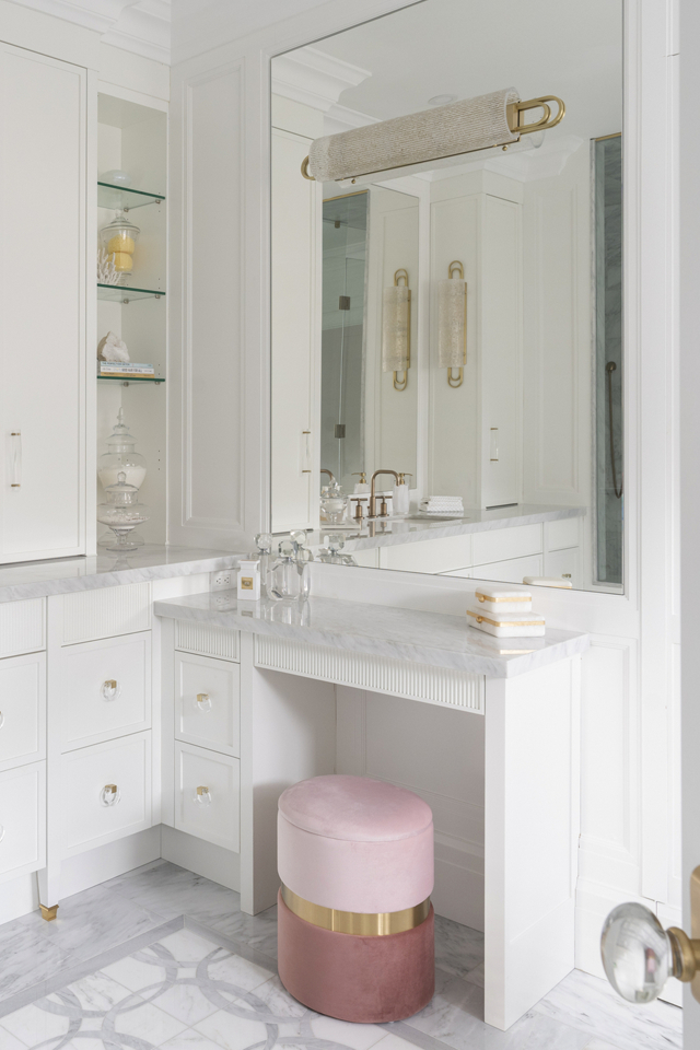 Bright white vanity in chic modern bathroom with pink seating and gold accents 
