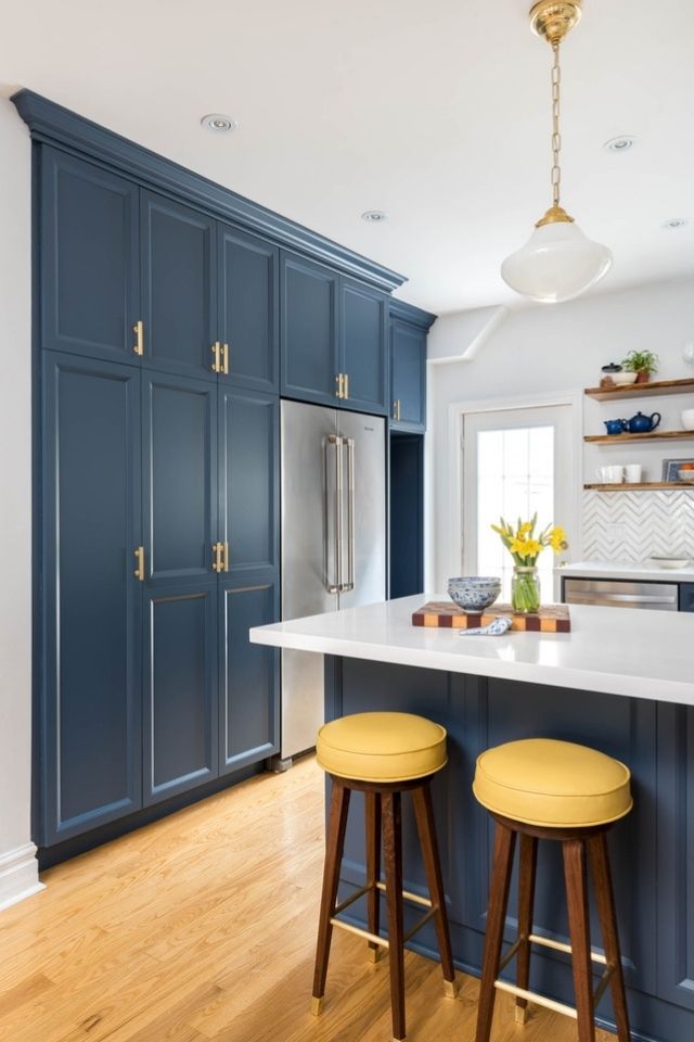 Pop of yellow on stools in blue and yellow kitchen with wood look floors